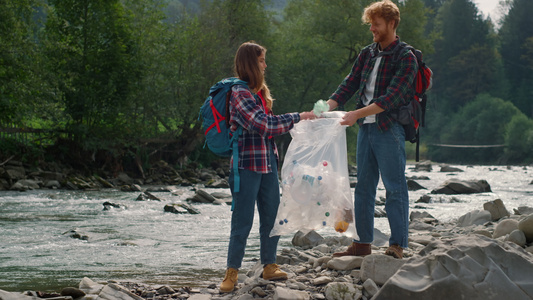 志愿人员在袋中收集瓶子 旅游者从人类垃圾中清除河流视频