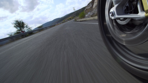 在大自然的道路上骑摩托车在崎岖不平的柏油路上关闭车轮18秒视频