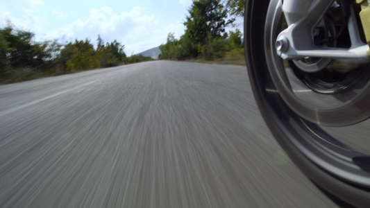 在大自然的道路上骑摩托车在崎岖不平的柏油路上关闭车轮视频
