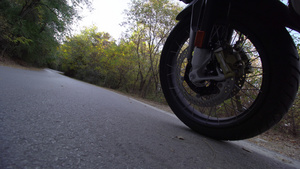 在大自然的道路上骑摩托车在崎岖不平的柏油路上关闭车轮18秒视频