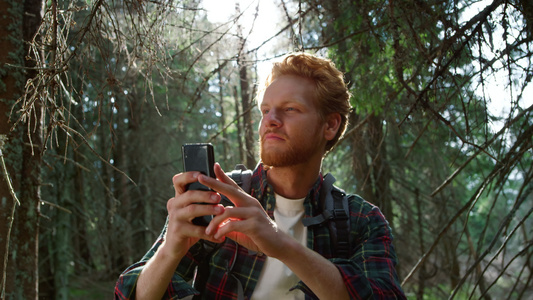 男人在森林里用智能手机拍照视频