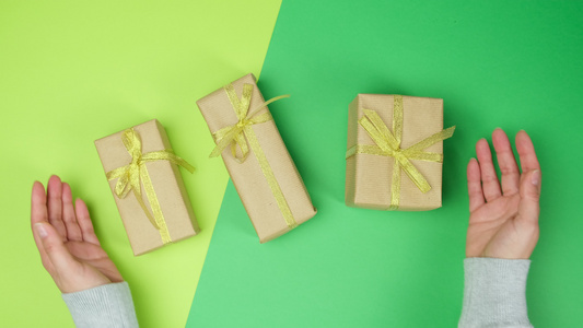 两只母的手在绿面上戴上一盒带金丝带绑着礼物的盒子视频