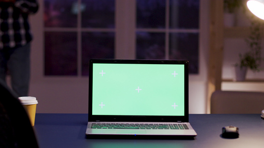 站在主办公台桌上的模拟绿色屏幕笔记本电脑视频