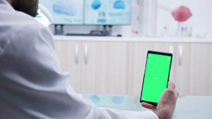握着绿色屏幕智能手机的医生16秒视频
