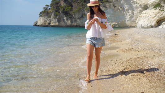 白沙滩热带海滩上的年轻美女帽子背景海滨的caucasian视频