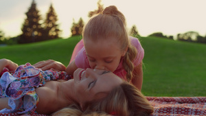 女人和孩一起在草地上笑 女儿在市公园里亲吻妈22秒视频
