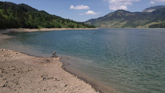 山上骑摩托车的人在湖边溜走在斯维兹兰的岩石海滩上兜风视频