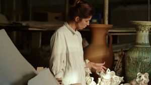 专注的女士在充满陶器的作坊里14秒视频