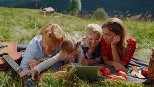 快乐的家庭休息平板电脑在绿色草地上阳光灿烂的日子视频