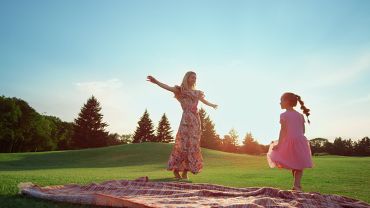 快乐的母亲和女儿一起在草地上跳舞视频