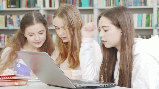 与朋友一起在图书馆学习时使用笔记本电脑的少女视频