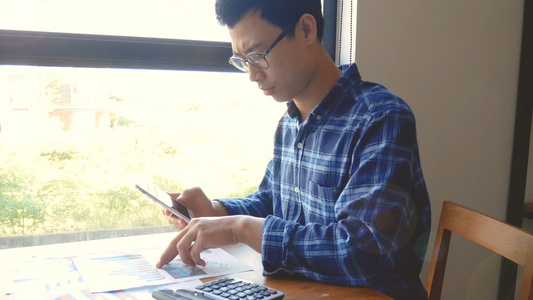 镜头严肃的亚洲商人处理文书工作和计算文件的计算器商业视频