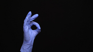 女性用乳胶手戴的医用手套在黑色背景上可以做一个好手势15秒视频