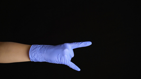 女性手放在乳胶式医疗手套上以黑色背景隔绝的岩石手势视频