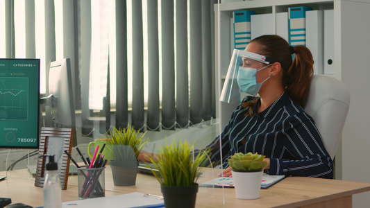 在新的正常办公室工作时带有保护面罩的经理视频
