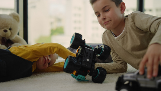 哥哥陪弟弟开心的在地毯上玩玩具车的孩子视频