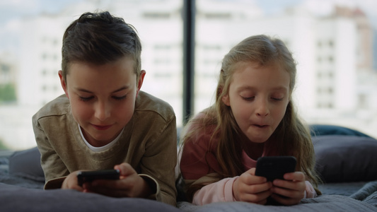 哥和姐在手机上玩游戏 小兄弟在家里用智能手机玩视频