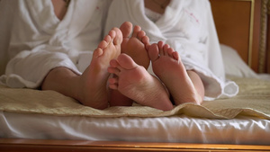 穿着浴袍的年轻夫妇坐在床上拥抱和握手10秒视频