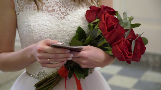 穿着结婚礼服的年轻新娘在室内盛放花束花白色豪华礼服视频