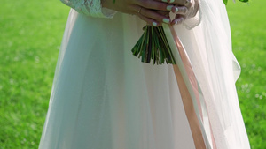 穿着结婚礼服的年轻新娘在公园里拿着花束花白色豪华礼服6秒视频
