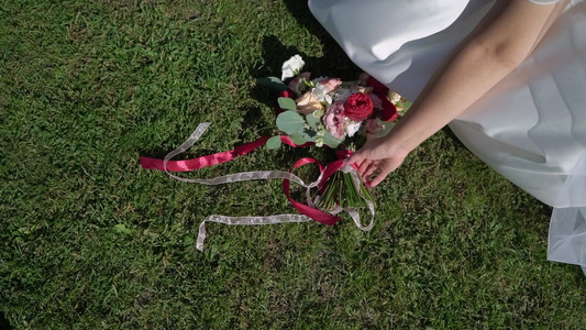 穿着结婚礼服的年轻新娘在公园里拿着花束花白色豪华礼服视频
