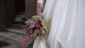 穿着结婚礼服的年轻新娘在城市里拿着花束花白色豪华礼服6秒视频