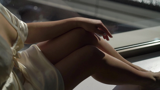 穿着白浴袍的女孩坐在窗边视频
