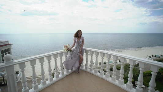 穿着内衣的年轻金发金发女子在露台穿着海观新娘花束视频