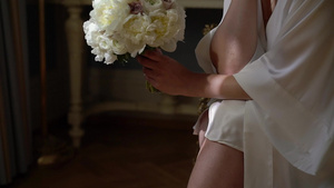 穿着内衣或浴袍的年轻美女鲜花新娘花束婚礼早上女人摆姿势6秒视频