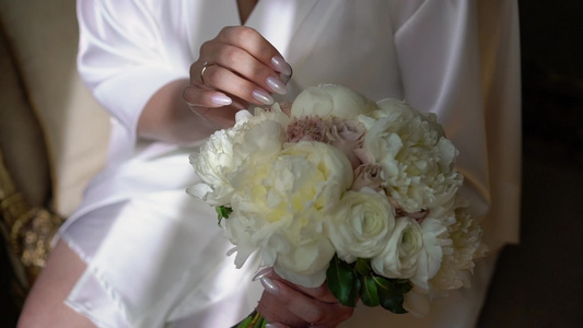 穿着内衣或浴袍的年轻美女鲜花新娘花束婚礼早上女人摆姿势视频