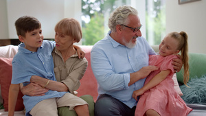 快乐的祖父和祖母坐在沙发上 孙子孙女坐在大腿上18秒视频