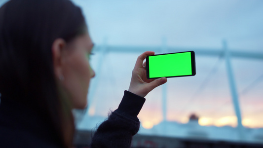 女孩用绿色屏幕在手机上拍照视频
