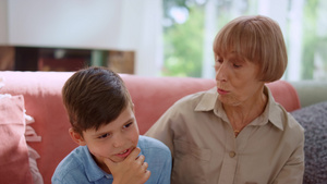 和祖母坐在沙发上的孙子手握着下巴17秒视频