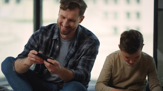 父亲和儿子在家使用智能手机玩游戏视频