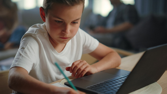 孩子在家写庭作业用笔记本电脑上网课视频