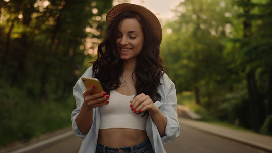 微笑的女人在公园里通过电话发短信视频
