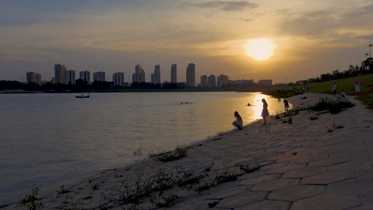 夕阳下在江边亲子玩水的人群4K素材视频