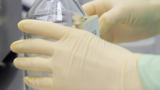 实验室工人用透明液体瓶装贴标签视频