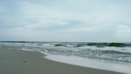 海浪在灰色多云的天气中撞击沙滩视频