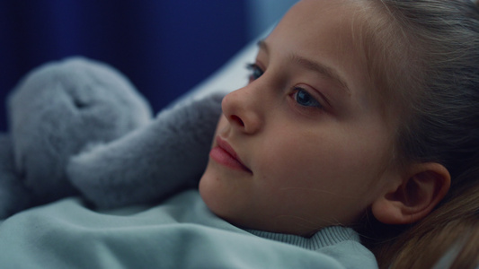 女孩躺在病床上带着毛绒玩具在儿科医院检查视频