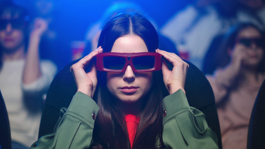 年轻女孩在电影院带着3d眼镜观看视频