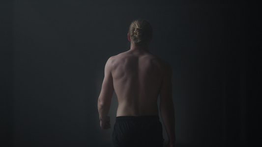 走在黑暗的走廊的男运动员背影视频