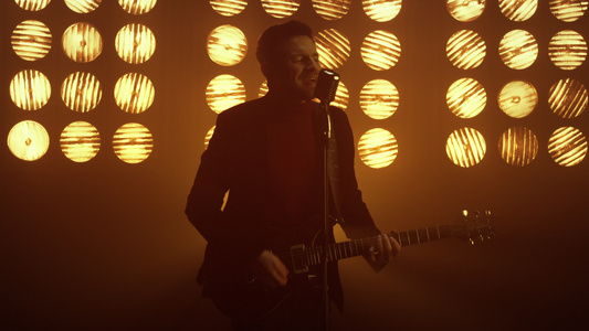 男人弹吉他在舞台上麦克风唱歌表演歌曲视频