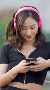 时尚女性戴耳机玩手机视频