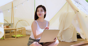 女孩坐帐篷里使用电脑6秒视频