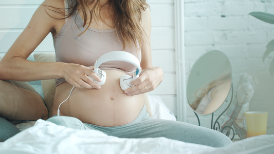 怀孕孕妈在家里给肚子里的宝宝进行音乐胎教视频