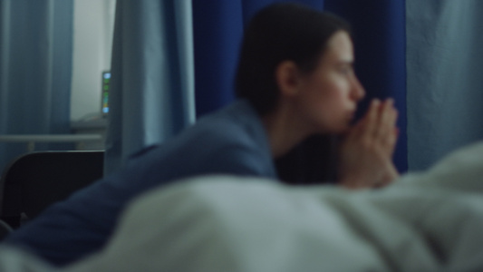 妈妈在手术后坐在病房里看着生病的睡着的女儿视频