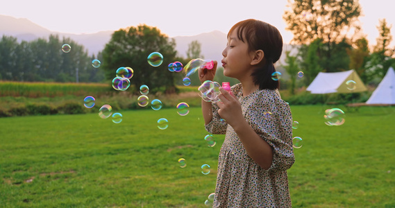 一个小女孩在草地上吹泡泡视频