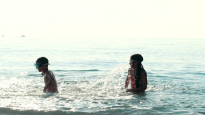 孩子在大海里游泳夕阳下剪影25秒视频