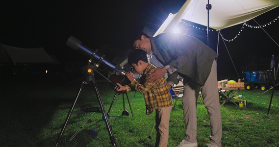 傍晚爸爸和儿子在露营地用望远镜看星空视频